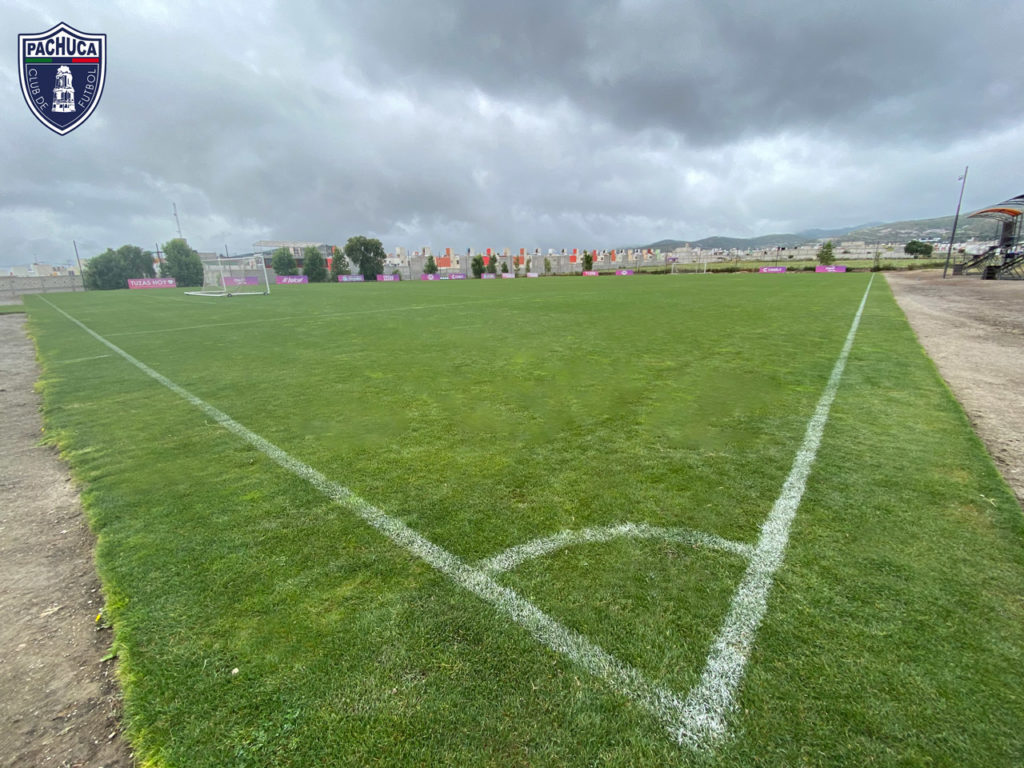 Cancha de pasto natural equipada con banquillos para dos equipos para uso de la Universidad del Futbol y primer equipo.